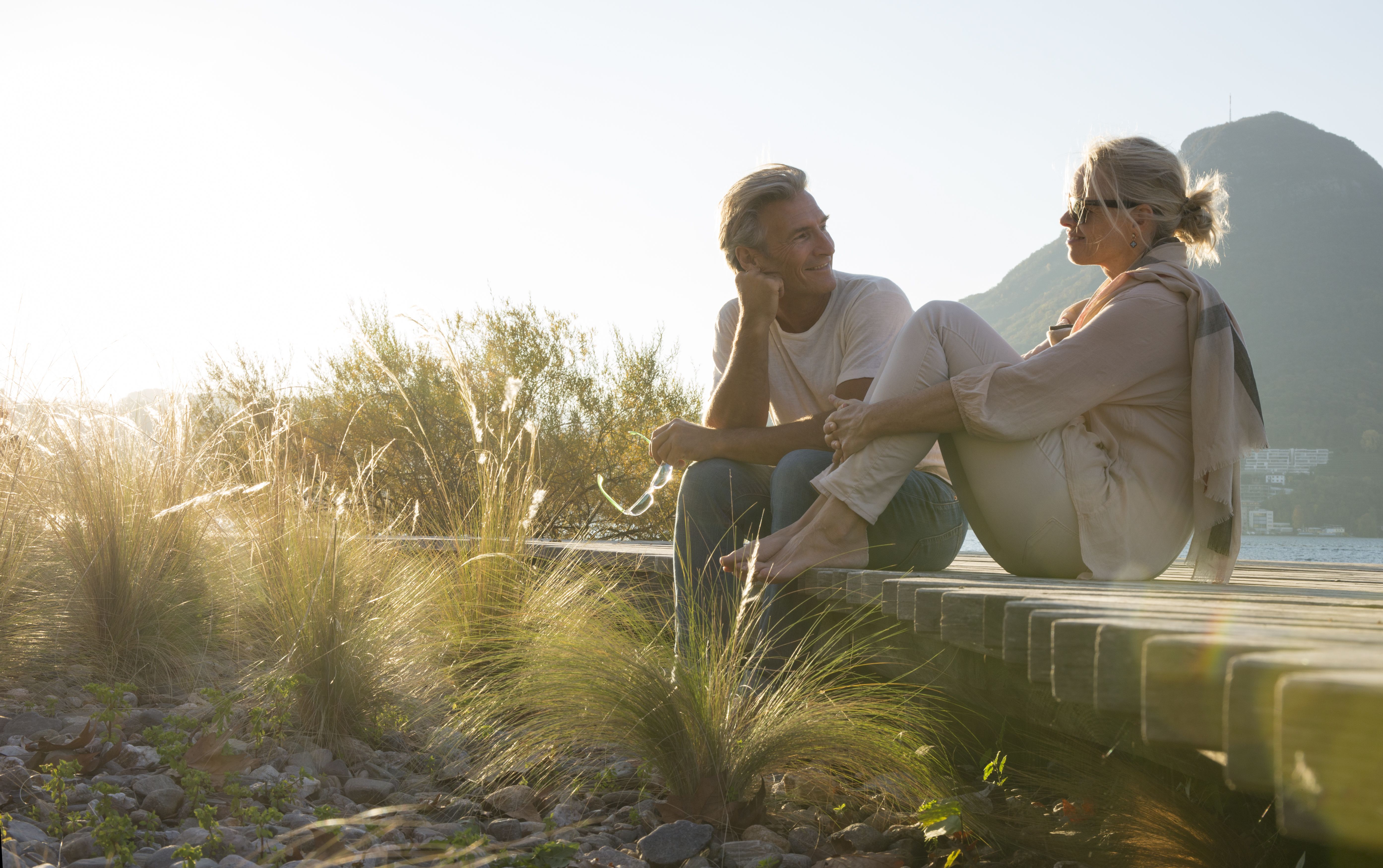 Un homme et une femme discutent dehors devant un paysage de montagne et font connaissance dans le cadre d’une recherche de partenaire sérieuse.