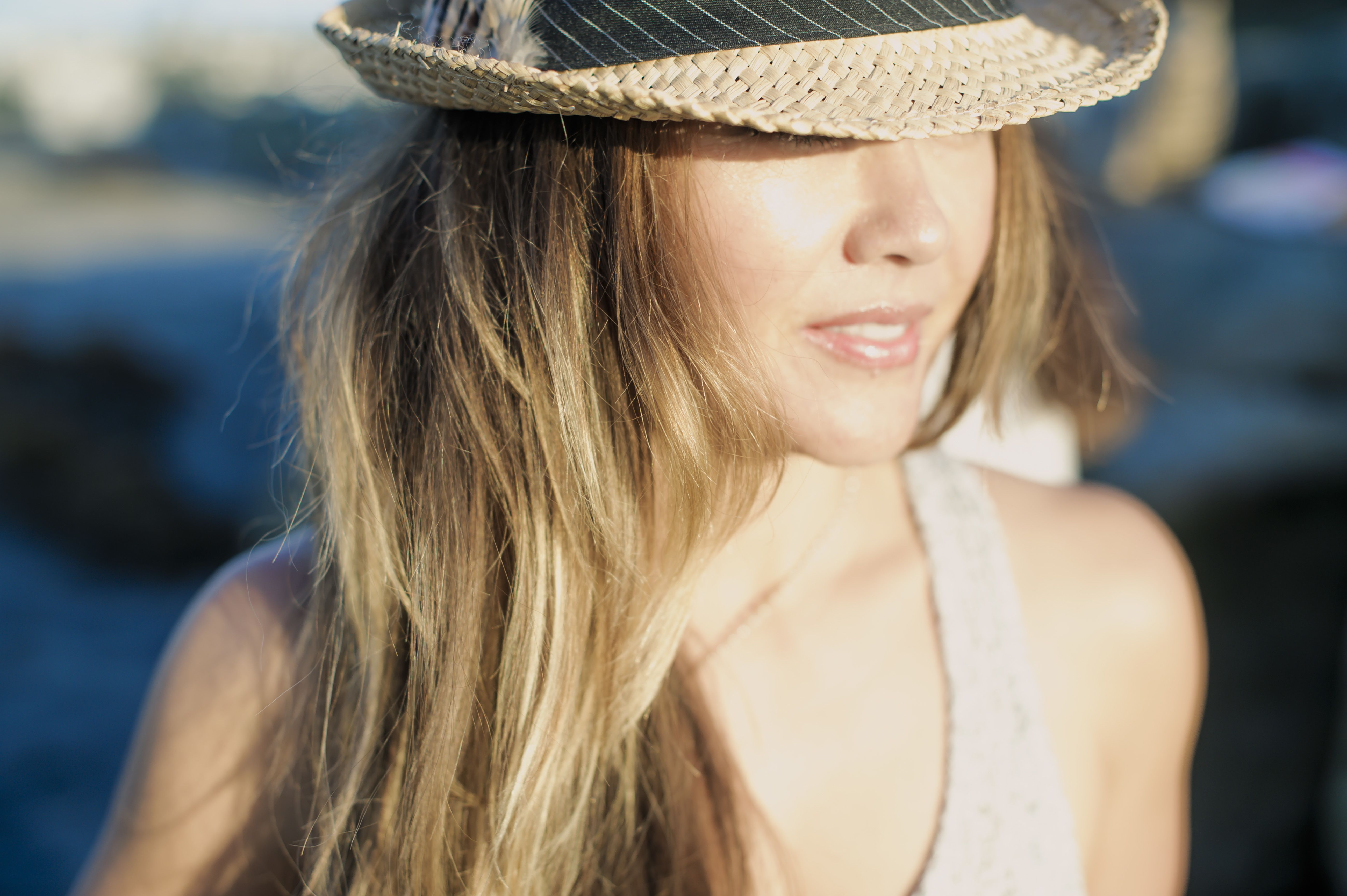 Femme portant un grand chapeau d’été, évoquant l’attirance, le charme d’une première impression et le désir de faire une rencontre authentique.
