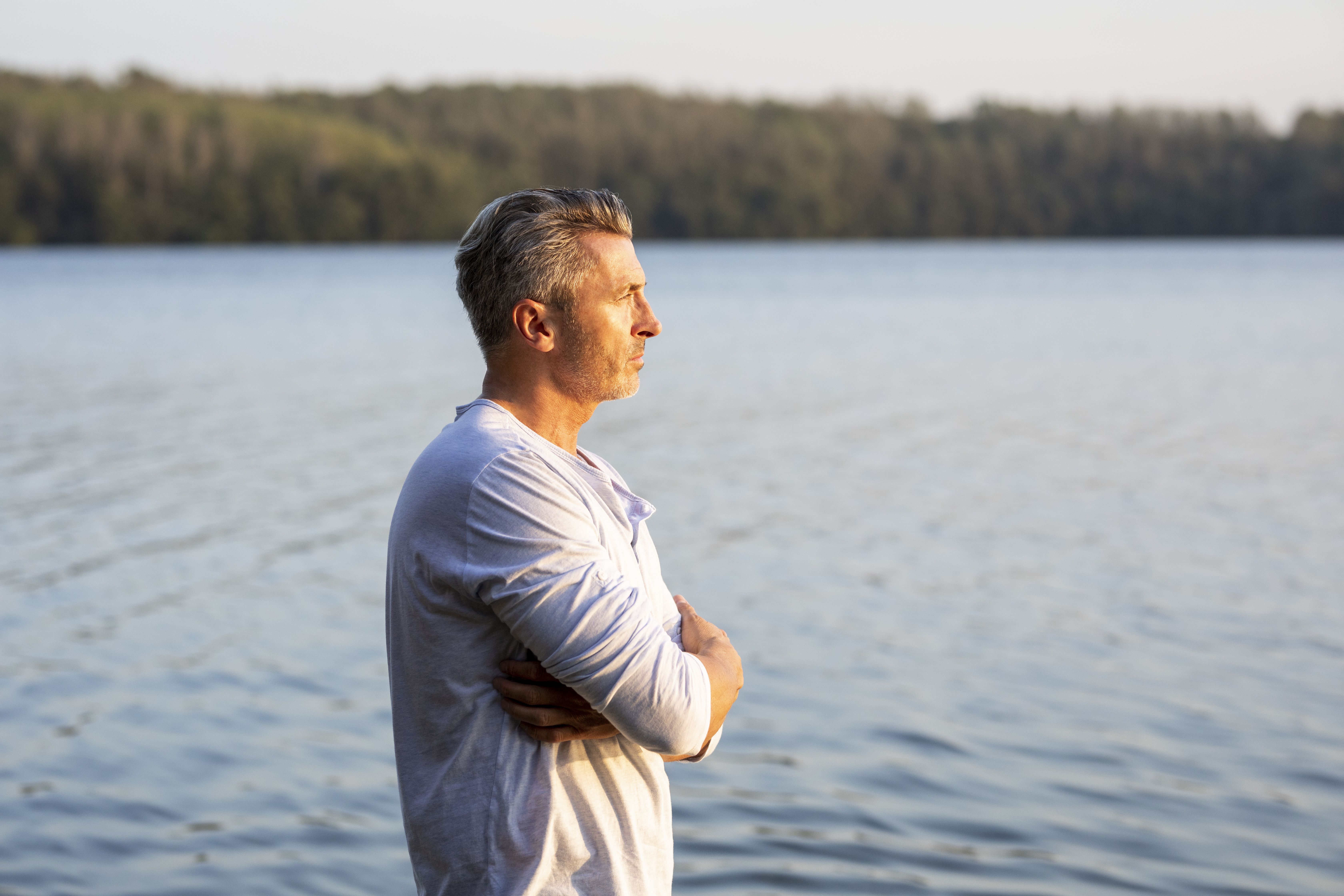 Homme d’une cinquantaine d’années contemplant un lac avec sérénité, illustrant un nouveau départ et la recherche d’une relation sérieuse après un divorce.