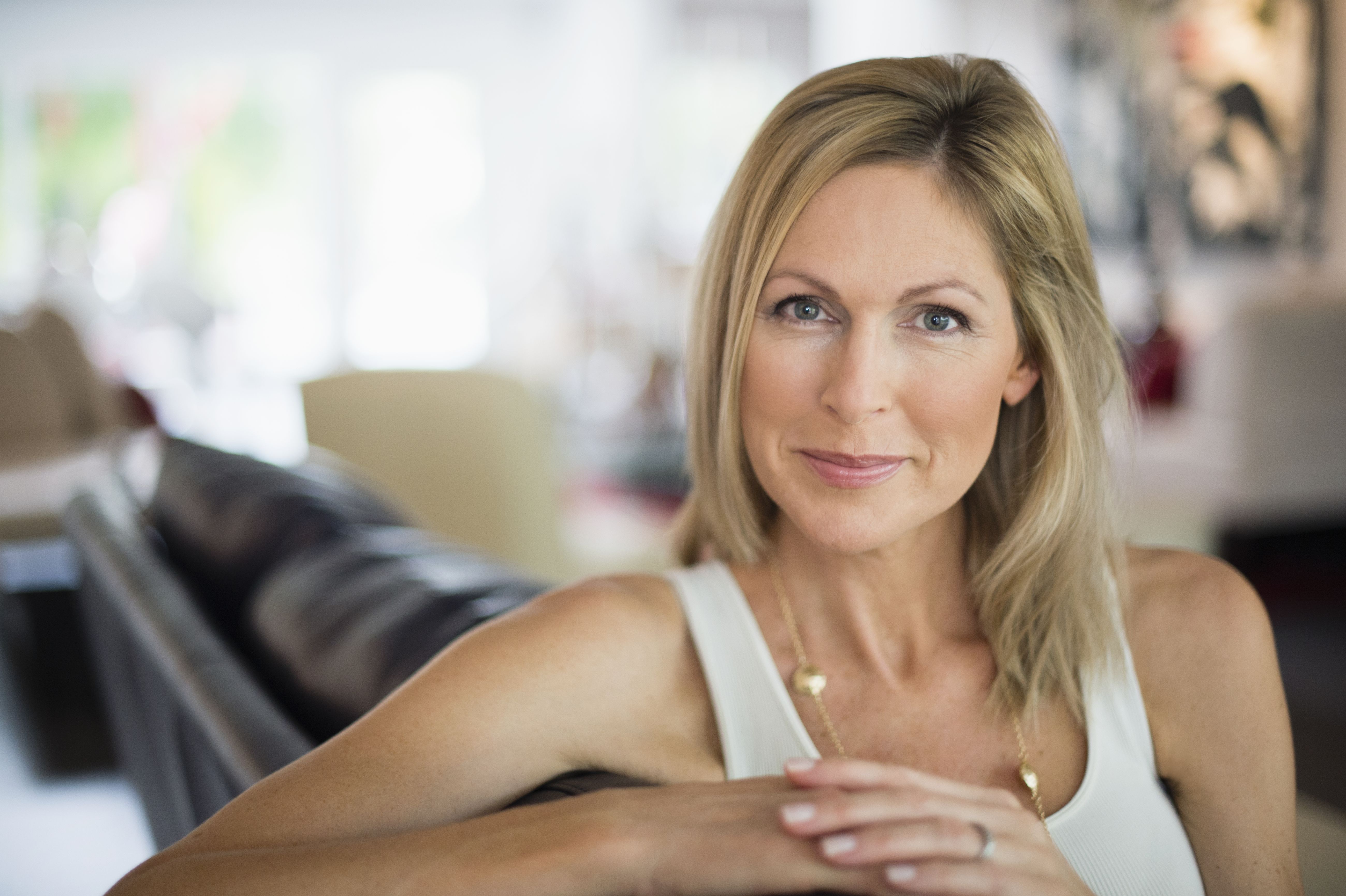 Femme de plus de 40 ans assise dans son salon, regardant l’objectif avec confiance, illustrant un nouveau départ et la recherche d’une relation sérieuse après un divorce.